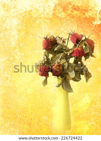 Withered rose bouquet on grungy red-orange painted wall background.