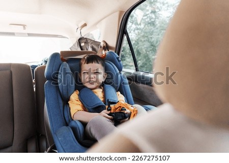 Cheerful smiling Asian little boy in safety car seat, Happy small child travel by car with family. Royalty-Free Stock Photo #2267275107