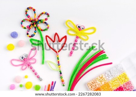 Beaded Pipe Cleaner flowers and dragonflies. Easy spring kids crafts. Different multi-colored supplies and materials for DIY art activity for kids. Children's crafts, creativity and  hobby.  Royalty-Free Stock Photo #2267282083