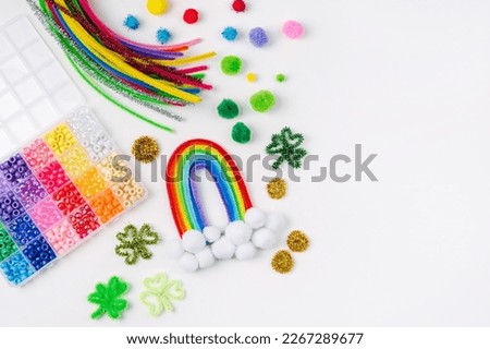 Rainbow and clover made of beads and pipe cleaners with different multi-colored  materials for DIY art activity for kids. Cute children's crafts of St Patrick's Day. Creativity and hobby.