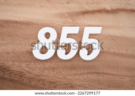 White number 855 on a brown and light brown wooden background.
