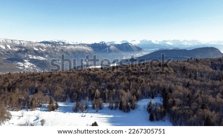 Panoramic view of snowy mountains in winter. Foggy mountains. Woods in front of the mountains.