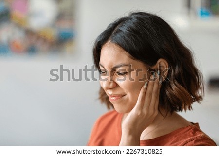 Sick young arab woman having ear pain at home, upset middle eastern female rubbing sore auricle with hand and frowning, suffering from otitis and acute ache, closeup shot with copy space Royalty-Free Stock Photo #2267310825