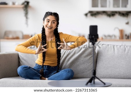 Young Indian Woman Making Bharatanatyam Hand Dance At Home While Recording Video For Social Networks, Happy Hindu Female Doing Finger Gestures At Camera, Using Smartphone On Tripod For Live Broadcast Royalty-Free Stock Photo #2267311065