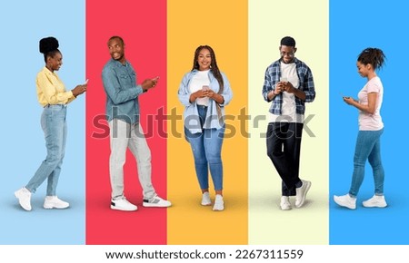 Smiling millennial black people in casual chatting on smartphone, typing on colorful background, studio, panorama, full length. Modern device for communication, app, great news, sale and new normal