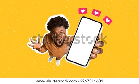 Top view of african american indignant man wearing glasses, raising hand with smartphone and screaming, showing phone white empty screen with heart icons above, full body, orange background, mockup Royalty-Free Stock Photo #2267311601