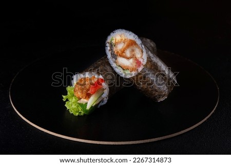 Japanese spring rolls with fish and caviar. Bright dish on a black plate.