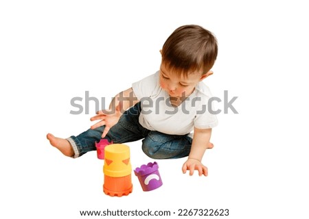 Toddler baby is playing logical educational games with a sandbox mold on a studio isolated on a white background. Happy child playing with an educational toy bucket. Kid aged one year four months