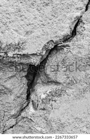 Big deep crack on wall with remnants of old plaster, abstract image of diagonal cleft. Black and white photo. Close-up. Vertical photo.  Copy space. Selective focus. Royalty-Free Stock Photo #2267333657