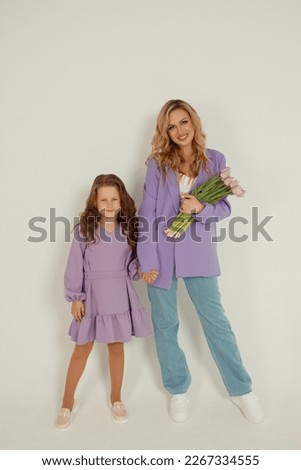 Young beautiful blonde mom with a little daughter with a bouquet of tulips