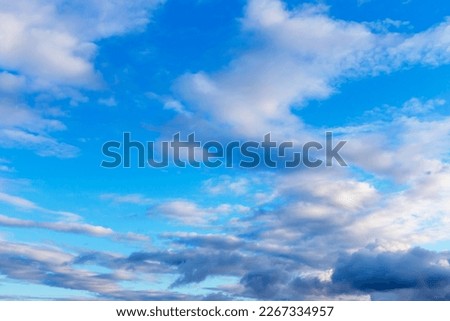 Dark and white fluffy clouds in the blue sky at sunset. Selective focus