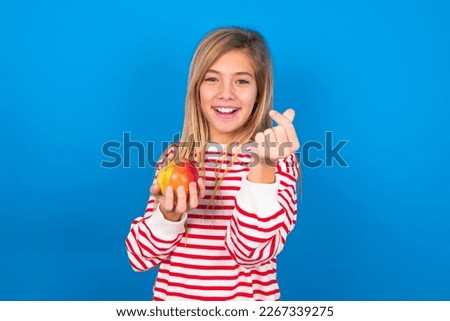 Beautiful caucasian teen girl wearing striped shirt over blue background smiling in love showing heart symbol and shape with hands. Romantic concept.