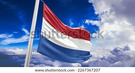 Netherlands national flag cloth fabric waving on beautiful blue sky.