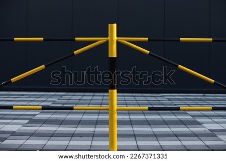 A fence with yellow and black stripes, in the background half of the image is a tile in the form of a cube and half is a dark gray color, good for the background