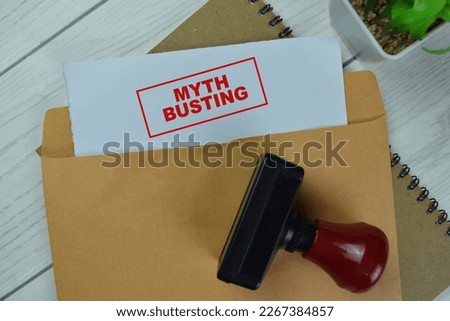 Concept of Red Handle Rubber Stamper and Myth Busting text above Brown envelope isolated on on Wooden Table. Royalty-Free Stock Photo #2267384857