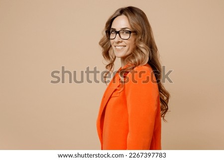 SIde view young fun happy successful employee business woman corporate lawyer 30s wears classic formal orange suit glasses work in office look camera isolated on plain beige color background studio Royalty-Free Stock Photo #2267397783