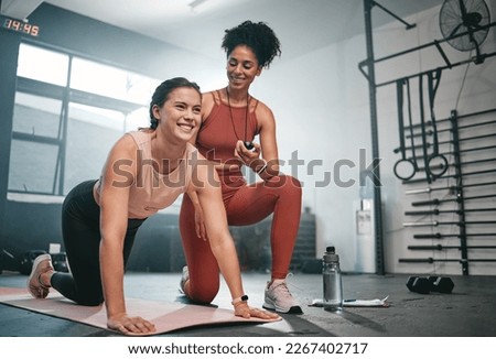 Personal trainer, exercise and stopwatch with a black woman coaching a client in a gym during her workout. Health, fitness or training and a female athlete ready to plank with a coach recording time Royalty-Free Stock Photo #2267402717