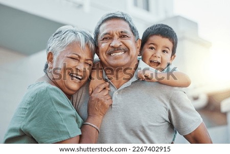 Grandparents, hug and child with smile for happy holiday or weekend break with elderly people at the house. Portrait of grandma and grandpa holding little boy on back for fun playful summer together Royalty-Free Stock Photo #2267402915