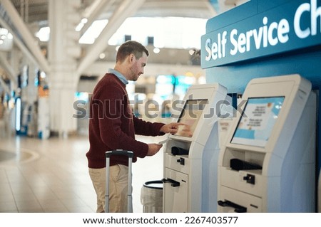 Man, airport and self service kiosk for check in, ticket registration or online boarding pass. Male traveler by terminal machine for travel application, document or booking flight with luggage Royalty-Free Stock Photo #2267403577