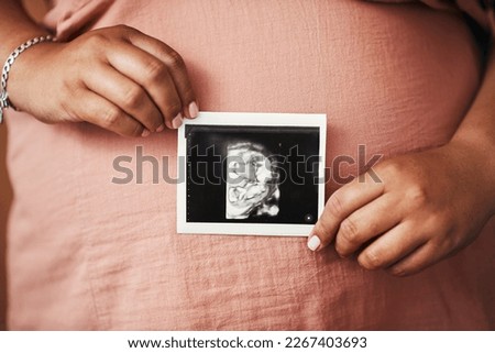 Meet the newest addition to the family. Closeup shot of an unrecognisable woman holding a sonogram in front of her pregnant belly.