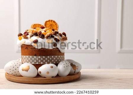 Traditional Easter cake with dried fruits and decorated eggs on white wooden table indoors. Space for text Royalty-Free Stock Photo #2267410259