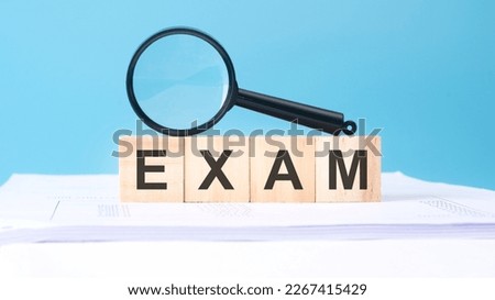 magnifying glass and wooden cubes with text EXAM, business concept