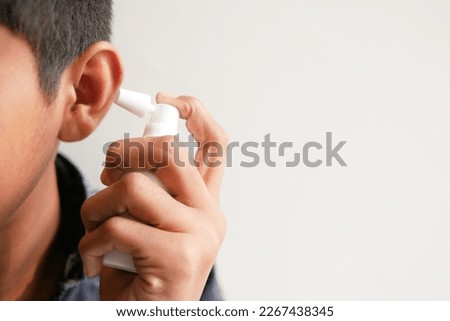 Close up of men using spray to remove earwax