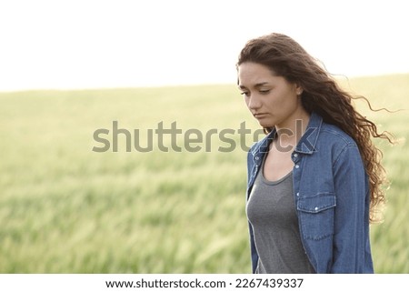 Sad woman walking alone in a wheat field Royalty-Free Stock Photo #2267439337