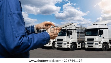 Manager with a digital tablet next to trucks. Fleet management