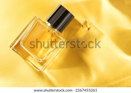 Transparent bottle of perfume on a yellow background with sun light caustic rays. Copy space. Royalty-Free Stock Photo #2267455261