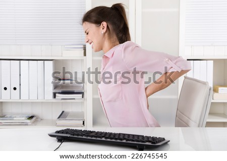Young woman sitting with backache in the office. Royalty-Free Stock Photo #226745545