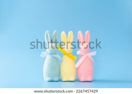 Pastel colored easter bunny decorations lined up on blue background
