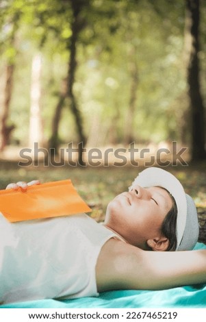 woman reading book and resting in forest