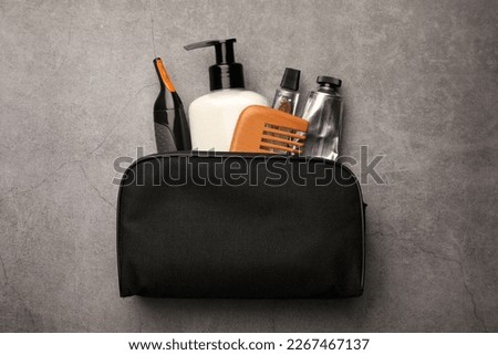 Preparation for spa. Compact toiletry bag with different cosmetic products on grey textured background, top view Royalty-Free Stock Photo #2267467137