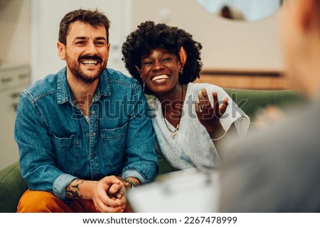 Young multiracial couple smiling because solved conflict at couple therapy session with a counseling adviser and. Diverse spouses being happy with a psychologist advises. Copy space. Royalty-Free Stock Photo #2267478999
