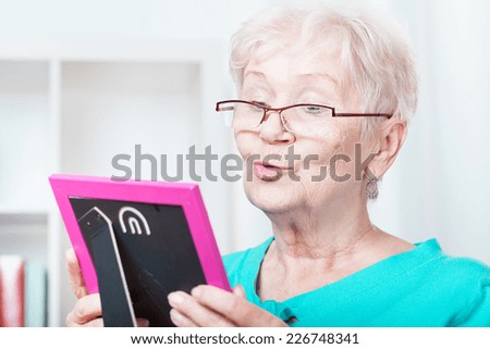 Elderly woman holding frame with family picture