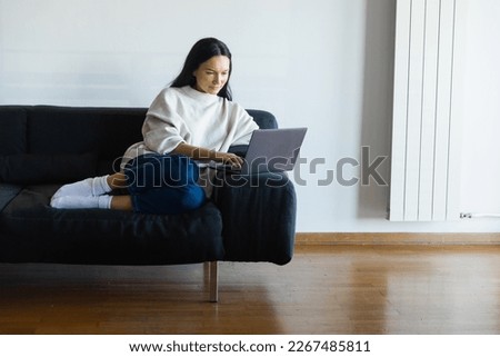 girl uses laptop on couch, work from home. High quality photo