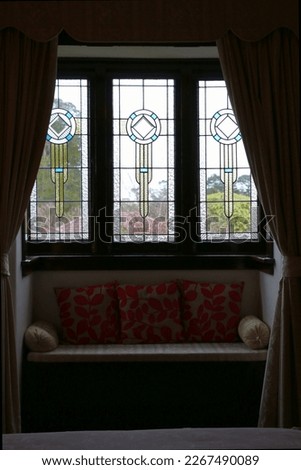 Ornate leaded glass windows and a window seat framed by long drapes provide the perfect reading nook in a traditional Federation style home in Katoomba, NSW, Australia. Royalty-Free Stock Photo #2267490089