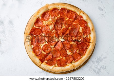 Sliced Pepperoni pizza on wooden board on concrete table top view