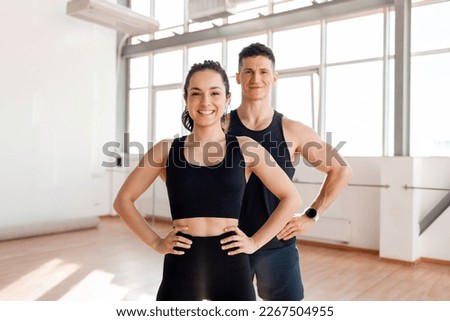 beautiful athletic couple in sportswear stands in the gym in the morning, fitness girl and coach man in training in bright room Royalty-Free Stock Photo #2267504955