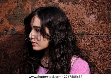 Profile portrait of teenage girl posing in gothic style dressed in black and pink colours with lost look