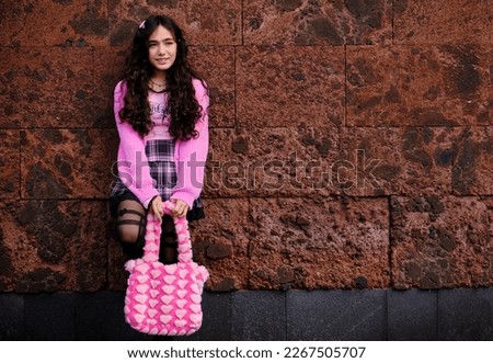 Teenager posing dressed in gothic style in black and pink posing looking at the camera.