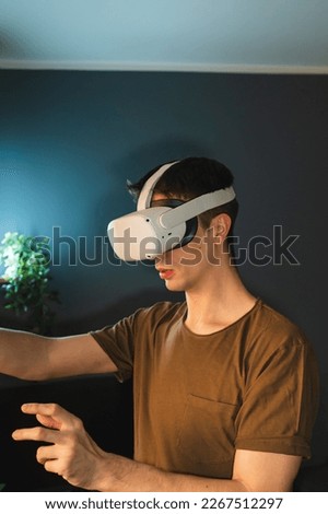 A young guy is wearing virtual reality googles or head set and playing in virtual reality in his room	
