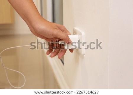 Hand insert a plug of the phone charger into socket.  Royalty-Free Stock Photo #2267514629