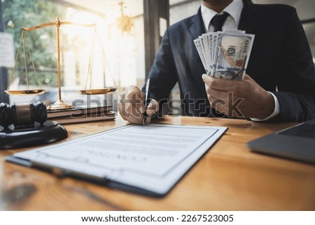 The young lawyer or Asian legal consultant holding money and signing an investment alliance contract The concept of corruption and embezzlement.