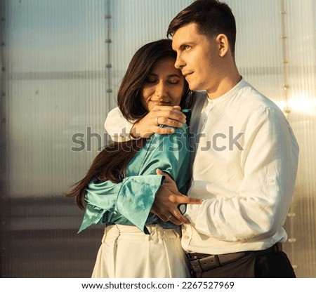 Young happy couple in love of different nationality hugging and kissingnear river. Asian woman and european man.