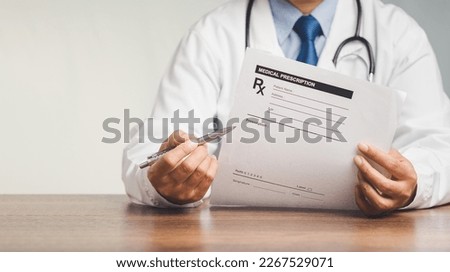 A doctor is holding a pen and a medical prescription while sitting in the hospital. Medical personnel, medicine, and science concept. Quality medical services Royalty-Free Stock Photo #2267529071