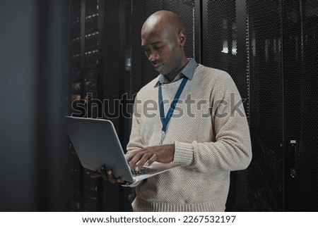 Laptop, server room and black man or technician in data center management, system or cybersecurity. Analysis, serious or power coding solution, engineering programmer or information technology person Royalty-Free Stock Photo #2267532197