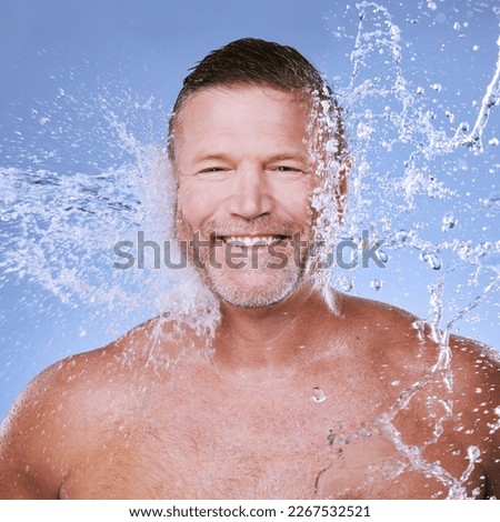 Portrait, mature man and water splash for skincare, morning routine or grooming on blue studio background. Face, male or gentleman with clear liquid, aqua or cleaning for dermatology, hygiene or wash