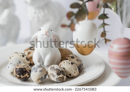 Banner. The concept of a bright Easter holiday. A bouquet of flowers with feathers, white rabbits and Easter eggs in a plate on a white isolated background. Beautiful Easter card.